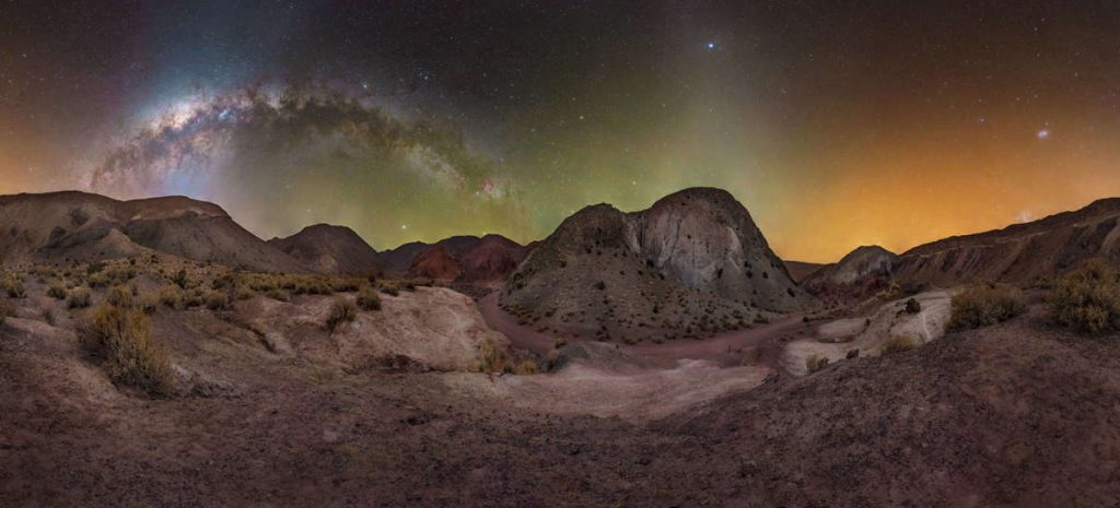 "Multicolored Up and Down!" por CARI LETELIER. Valle Arcoiris, Desierto de Atacama, Chile. "Esa noche, reinaba el silencio, lo que nos permitía ver nuestras sombras iluminadas únicamente por el brillo de las estrellas. Para capturar esta escena, creé una panorámica de 360°x90° con 65 fotografías utilizando una cámara astromodificada y una cabeza panorámica"