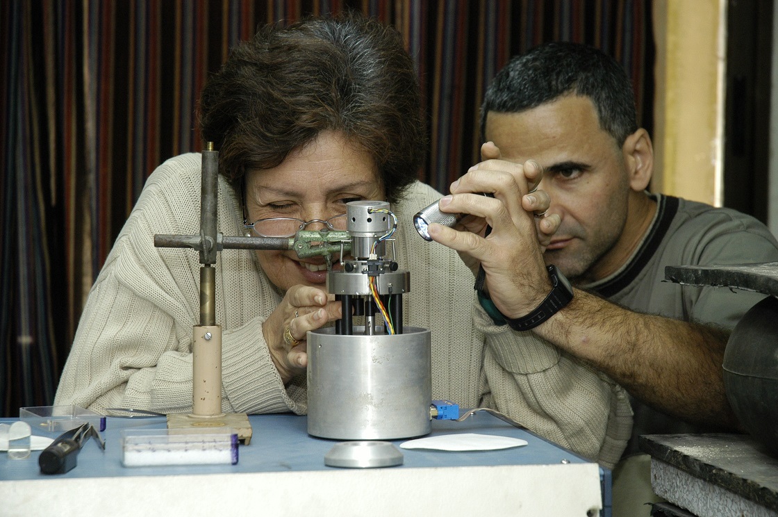 La Doctora en Ciencias Físicas Mayra Hernández y el maestro Carlos Canino con el microscopio de efecto túnel. Linterna en mano, observe que la punta de la aguja está lo suficientemente próxima a la muestra como para iniciar el barrido.